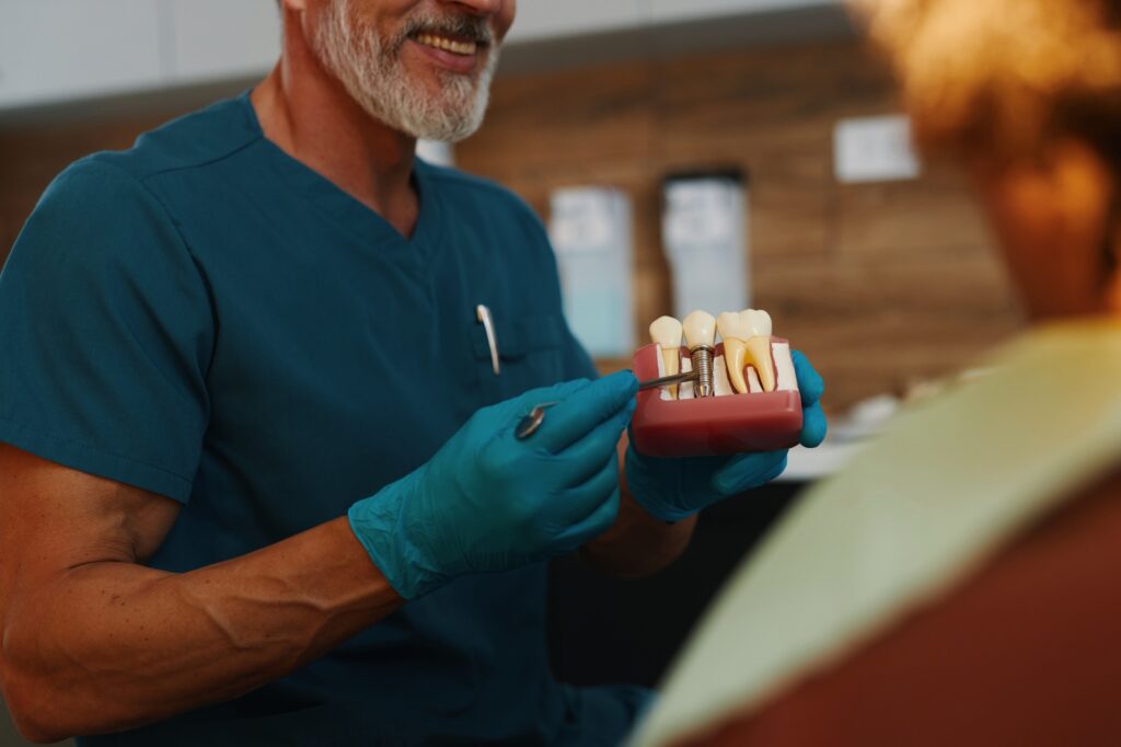 Smiling Dentist Displaying Dental Implants to Female Patient